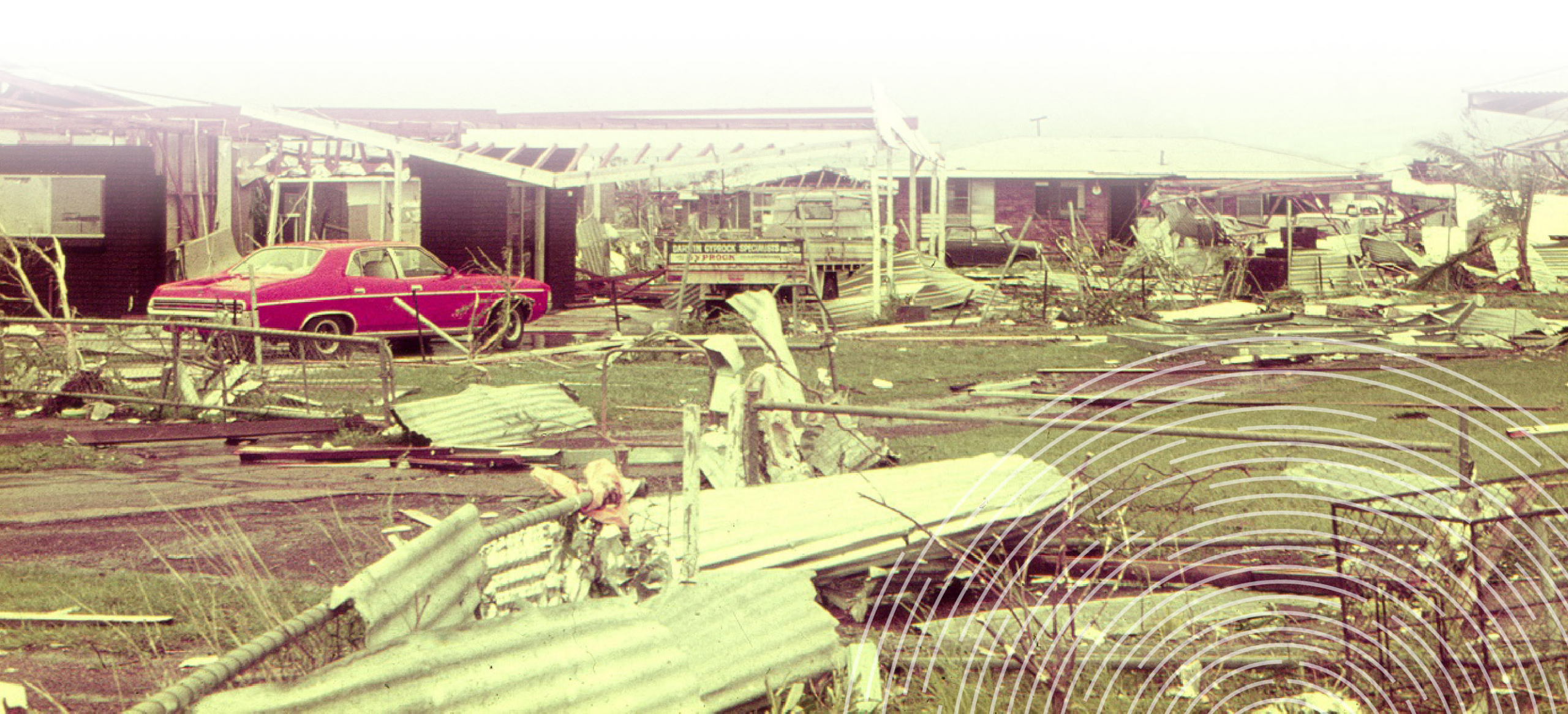 Destruction of buildings in Darwin after Cyclone Tracy, featuring severe structural damage and a red car undamaged amidst the debris.